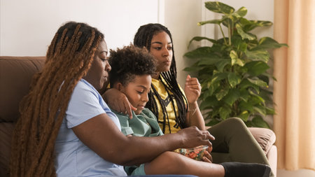 Happy family having popcorns while watching TV as they sit on sofaの写真素材