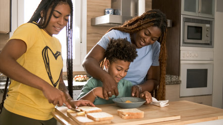Happy mother assisting son in mixing egg yolk with daughter in kitchenの写真素材