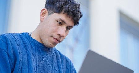 Young latin american student working on laptop outdoorsの写真素材