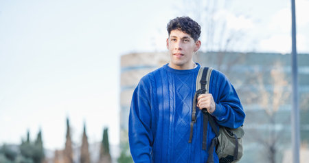 Young latin american student walking outside university campus building