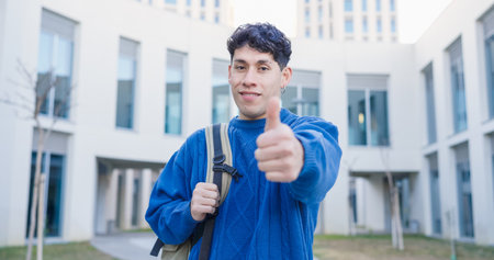 Smiling university student gesturing thumbs up outdoorsの写真素材