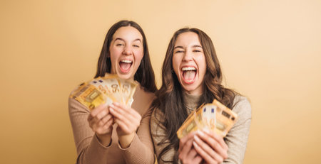 Excited women celebrating with euro banknotesの写真素材