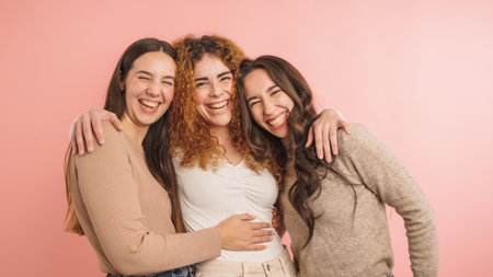 Three women embracing and laughing togetherの写真素材