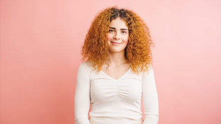 Young woman smiling with long red hair on pink backgroundの写真素材