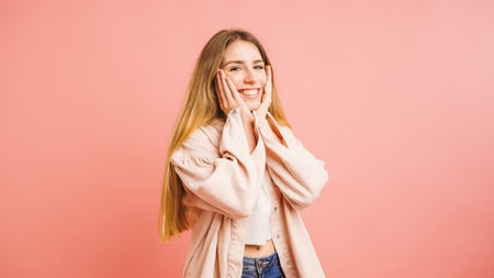 Cheerful blonde woman expressing excitement on pink backgroundの写真素材