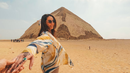 Tourist holding hand and leading towards bent pyramid in egyptの写真素材