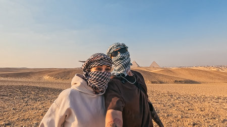 Tourists wearing keffiyeh taking selfie in giza with pyramids in backgroundの写真素材