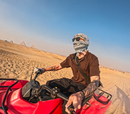 Tourist riding quad bike exploring giza pyramids in egypt desertの写真素材