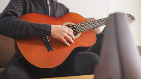 Young musician playing acoustic guitar at homeの写真素材