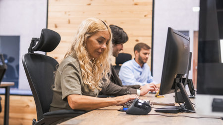 Businesswoman using computer with colleagues working in backgroundの写真素材
