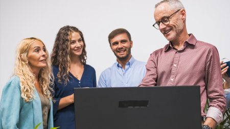Group of colleagues laughing and engaging with a laptop during a casual meeting.の写真素材