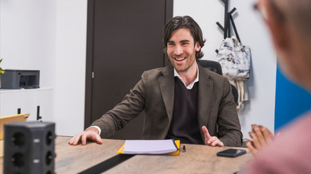 Happy young businessman sitting at desk during conference meetingの写真素材