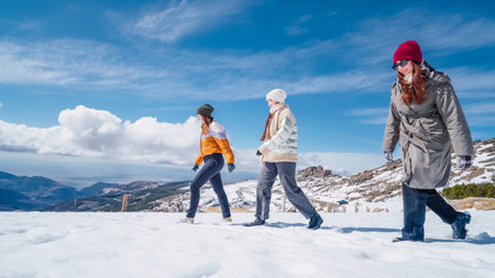 Three women hiking in snowy mountain landscape on sunny winter dayの写真素材