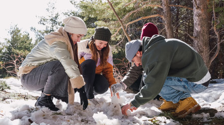 Friends building snowman together in snowy woods