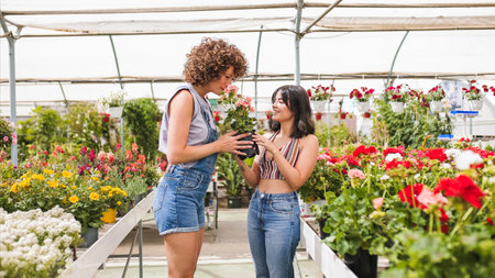 Young women smelling blooming flowers inside greenhouse nurseryの写真素材