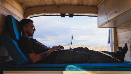 Freelancer working remotely on laptop in camper van at gorafe, spain