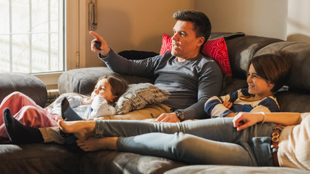 Family relaxing on sofa watching television togetherの写真素材