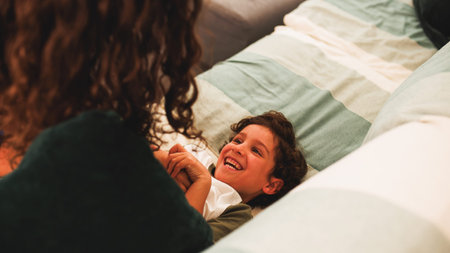 Happy child lying on bed playing with mother