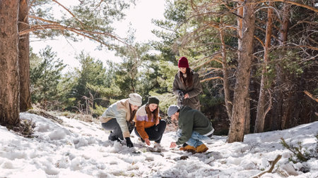 Friends playing in the snow under pine trees in winter forest