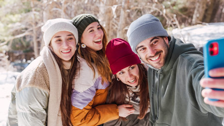 Happy friends taking selfie in snowy mountain landscapeの写真素材
