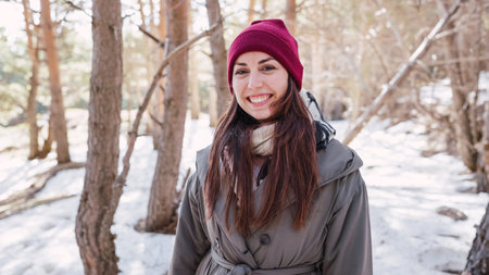Young woman smiling in snowy forest during winter