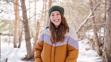 Young woman smiling in snowy forest wearing winter clothes