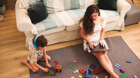 Mother working from home while child plays with building blocksの写真素材
