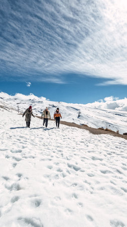 Tourists walking on snow covered mountain on sunny day