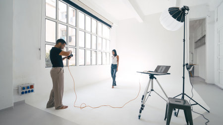 Photographer working with model in professional studio with laptop and lighting equipmentの写真素材