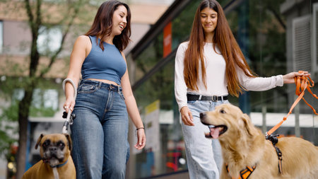 Women friends walking dogs in city street