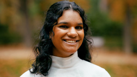 Indian woman smiling outdoors during autumn