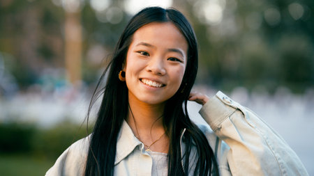 Young Asian woman smiling looking at camera outdoors