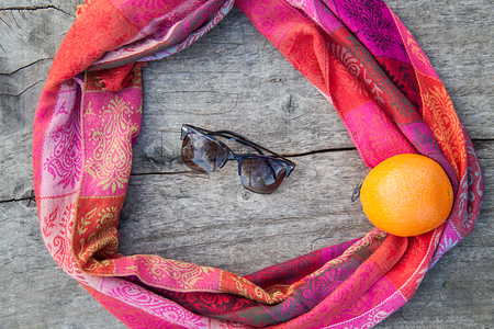 Sunglasses on a wooden table, orange and a woman's scarfの写真素材