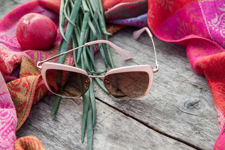 Unusual composition of sunglasses and onion on a woman's scarf on the wooden boardの写真素材