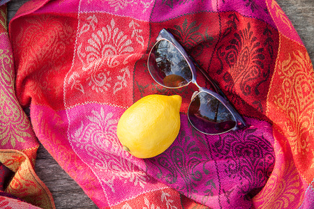 Unusual composition of sunglasses and lemon on a woman's scarfの写真素材