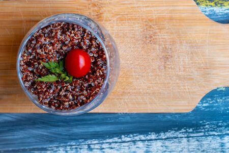 Red quinoa salad with tomato on a rustic table. Superfood and healthy eating concept.の写真素材