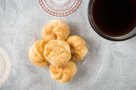 a plate of choux cream with a cup of coffee on the tableの写真素材