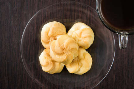 a plate of choux cream and a cup of coffee on the wood tableの写真素材