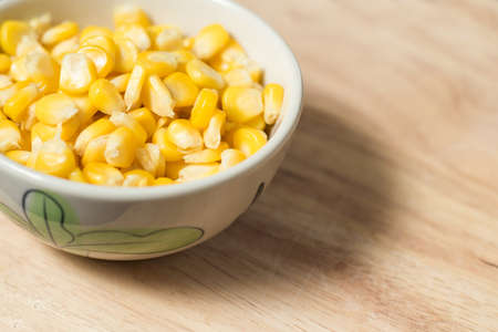 a bowl of corn seed on a wood block as a backgroundの写真素材