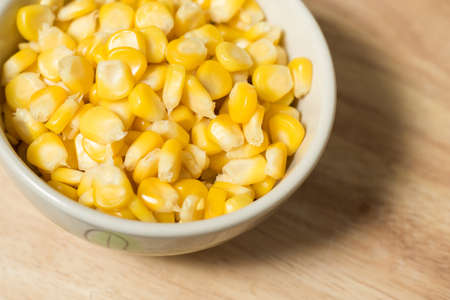 a bowl of corn seed on a wood block as a backgroundの写真素材