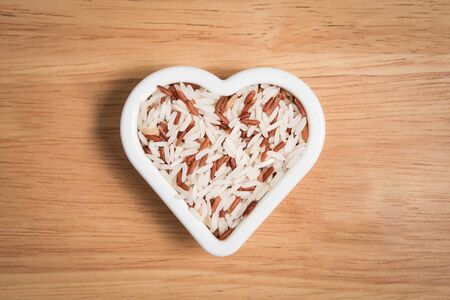 brown rice in a heart block shape on the wood backgroundの写真素材