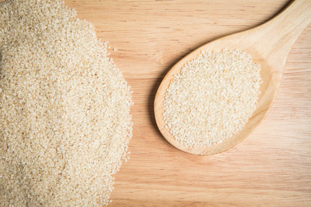scoop of sesame and a pile of sesame on a wooden backgroundの写真素材