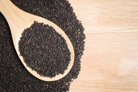 scoop of black sesame and a pile of black sesame on a wooden backgroundの写真素材