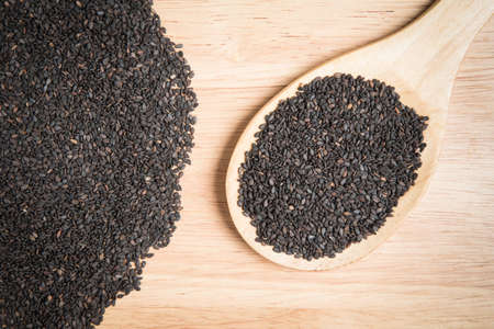 scoop of black sesame and a pile of black sesame on a wooden backgroundの写真素材