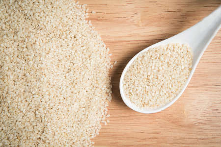 spoon of sesame and a pile of sesame on a wooden backgroundの写真素材