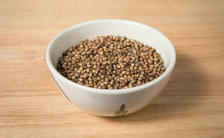 bowl of dried coriander seed on a wood background