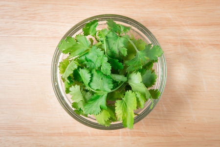 bowl of  coriander leaf on a wooden blockの写真素材