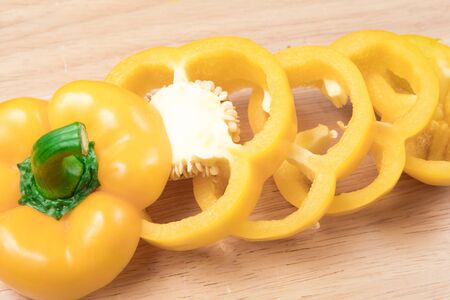 sliced yellow sweet pepper on a wooden blockの写真素材