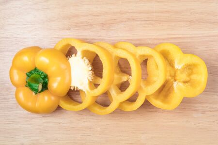 sliced yellow sweet pepper on a wooden blockの写真素材