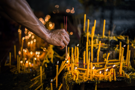 A hand of a man try to ignite an incense with a candleの写真素材